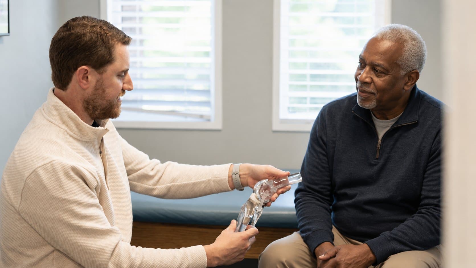 Dr. Seem walking a patient through a knee replacement model in the exam room